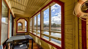 A room with a wooden ceiling, large windows, a table, and a bench.