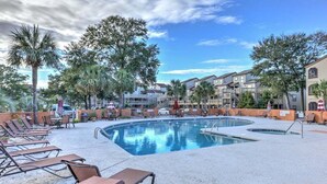A pool area with lounge chairs and a building in the background.