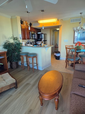 Un salón espacioso con una mesa de centro de madera, un comedor con candelabro y una cocina con electrodomésticos modernos.
