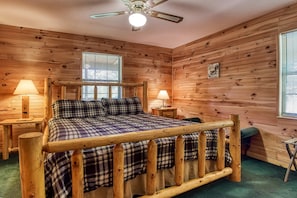 A wooden-paneled bedroom with a bed, two bedside lamps, a ceiling fan, and a window. - Sunset Ridge - Near Dollywood! Jacuzzi! Fireplace! Pool Table! Large Game Room! (Pigeon Forge)