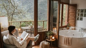 A cozy room with a large window, a bathtub, and a table with chairs. - Magical Place, Ideal Couples: Jacuzzi, Mountains, Barbecue And Fireplace (Asturias)
