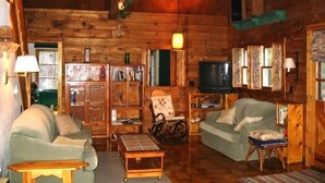 L’intérieur d’un chalet confortable, avec un canapé, un fauteuil et une petite table.