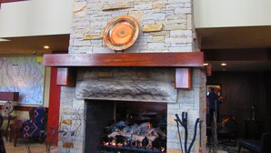 Una chimenea de piedra con fuego, rodeada de paredes de piedra y vigas de madera.