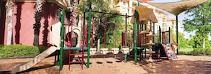 Kids can play under the shade of a canopy in this outdoor playground with a slide, climbing frames, and swings.