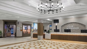 A hotel reception area with a modern design, a reception desk, and a chandelier.