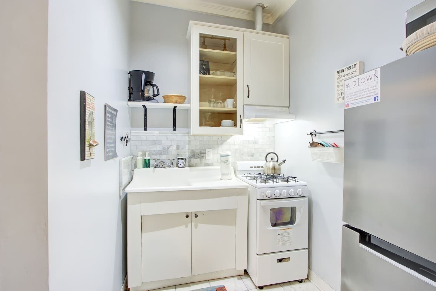 A compact kitchen with white cabinets, a stove, and a refrigerator.