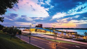 A modern building with a curved roof, a pedestrian walkway, and a view of the water.
