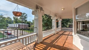 Une véranda couverte avec un plancher en bois, des balustrades blanches et des colonnes.