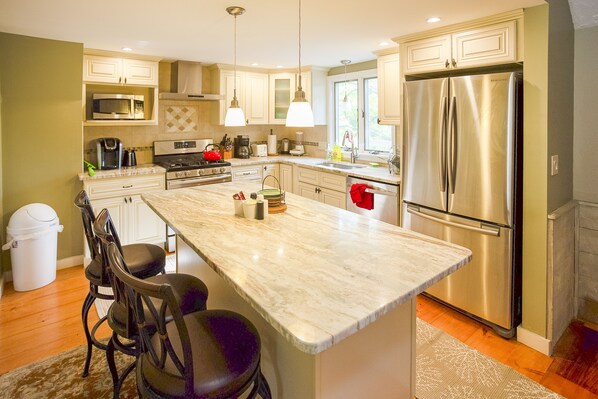 A modern kitchen with a large island, stainless steel appliances, and pendant lighting.