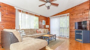 Una sala de estar con un sofá modular, una mesa de centro, un televisor y piso de madera.