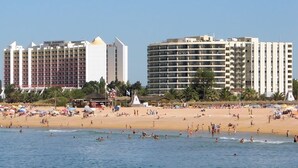 Una playa con un hotel y un complejo turístico al fondo.