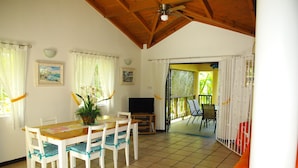 A dining area with a wooden table and chairs, a television, and a plant.