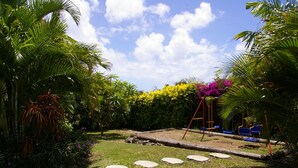 A garden with stone steps, palm trees, and colorful flowers.