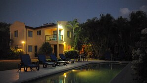 A poolside area with lounge chairs and a building with multiple balconies.