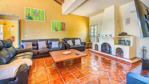 Una sala de estar con chimenea, sofás de cuero y piso de baldosas.