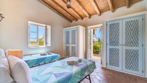 Un dormitorio con dos camas, una ventana y una puerta que da a un espacio exterior.