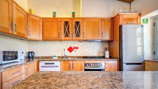 Una cocina con armarios de madera, microondas, estufa y refrigerador.
