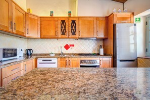 A kitchen with wooden cabinets, a microwave, a stove, and a refrigerator.
