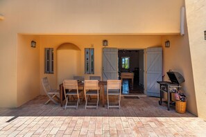 An outdoor patio with a table and chairs, a grill, and a basket.
