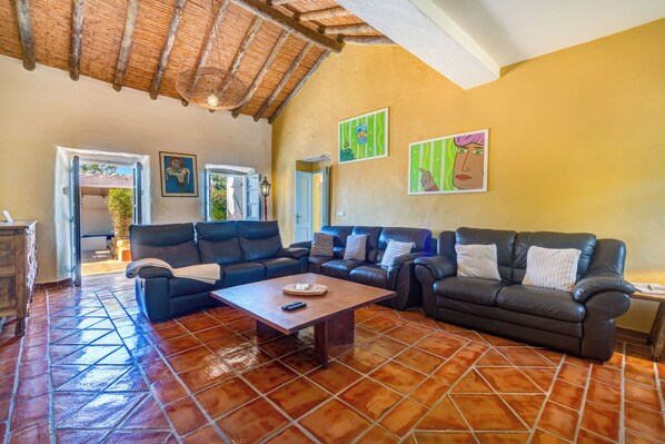 A spacious living room with a large sofa set, a coffee table, and a tiled floor.
