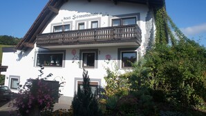 A two-story building with a balcony, windows, and a sign reading "haus Sonnenschein".