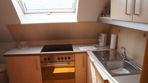 A compact kitchen with a built-in oven, a sink, and a window above the countertop.