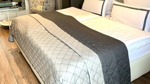 A hotel room with a large bed, a wardrobe, a desk with a lamp, and a mirror.