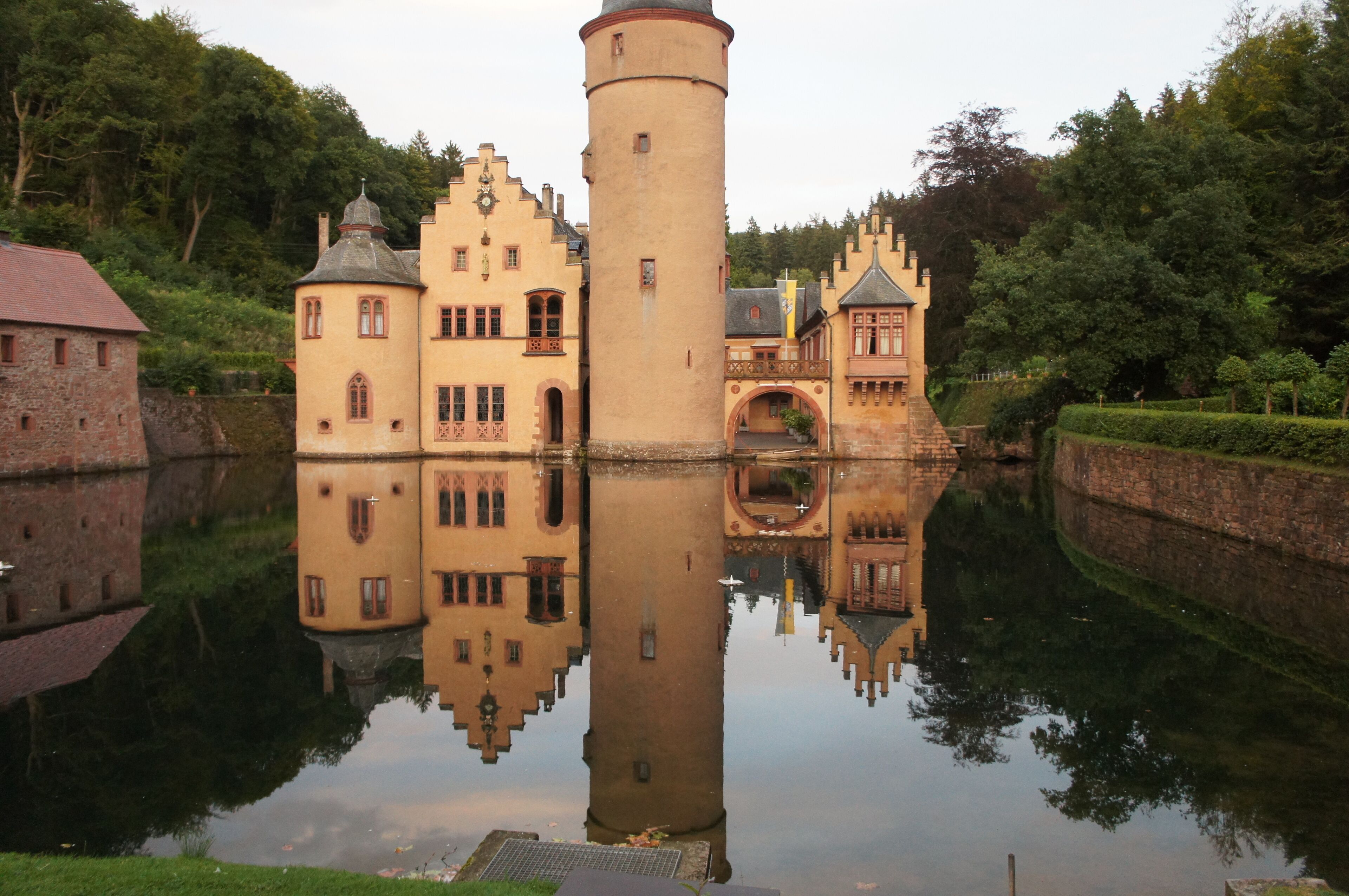 Un château doté d’une tour centrale, entouré d’eau et de verdure.