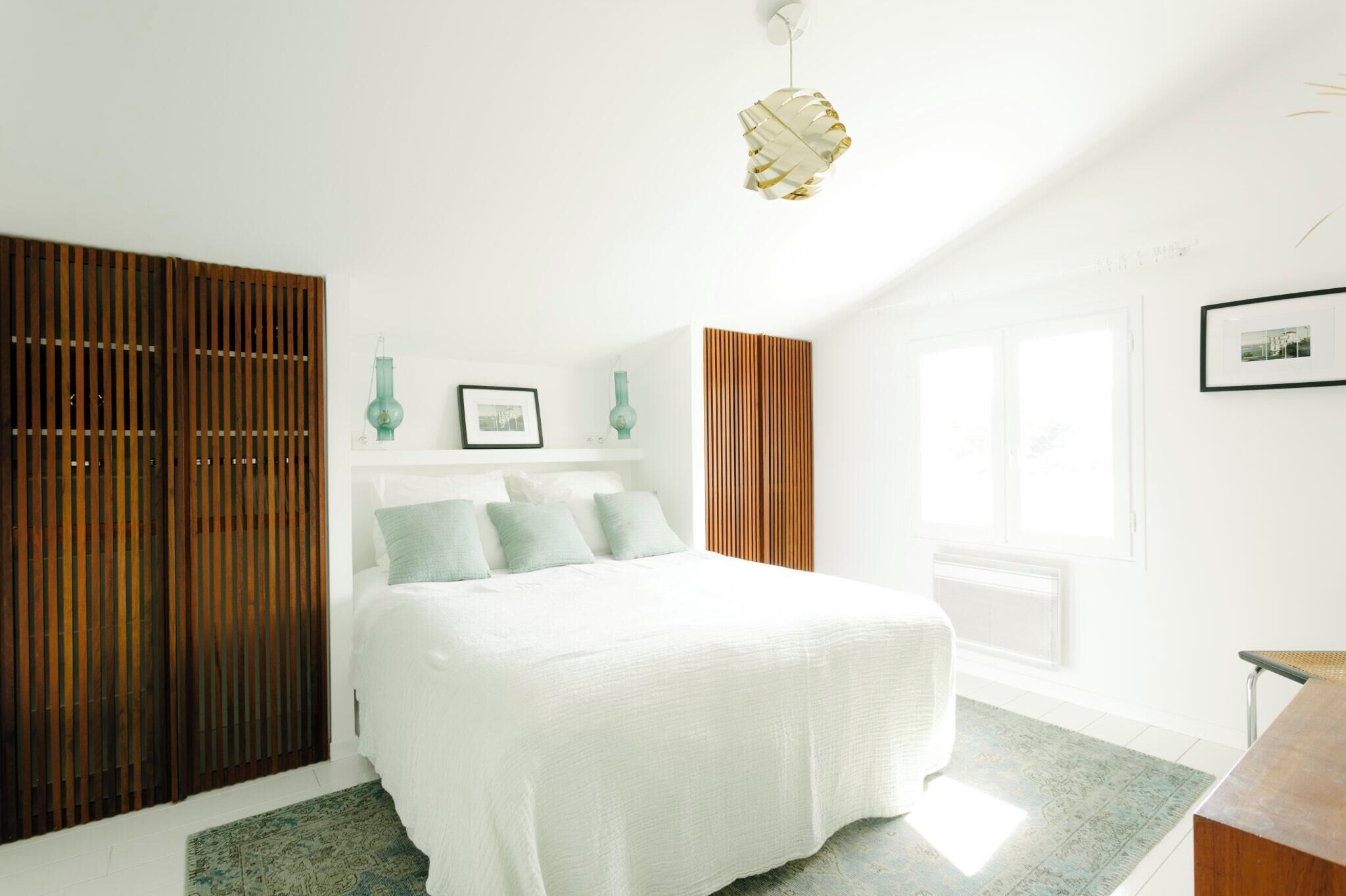 Une chambre avec un grand lit, une armoire en bois et une fenêtre donnant sur un beau paysage.