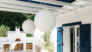 An outdoor dining area with a white table set for six, blue and white plates, and a vase with pink flowers. - House center Guethary Maisons Dominos 1 (Guéthary)