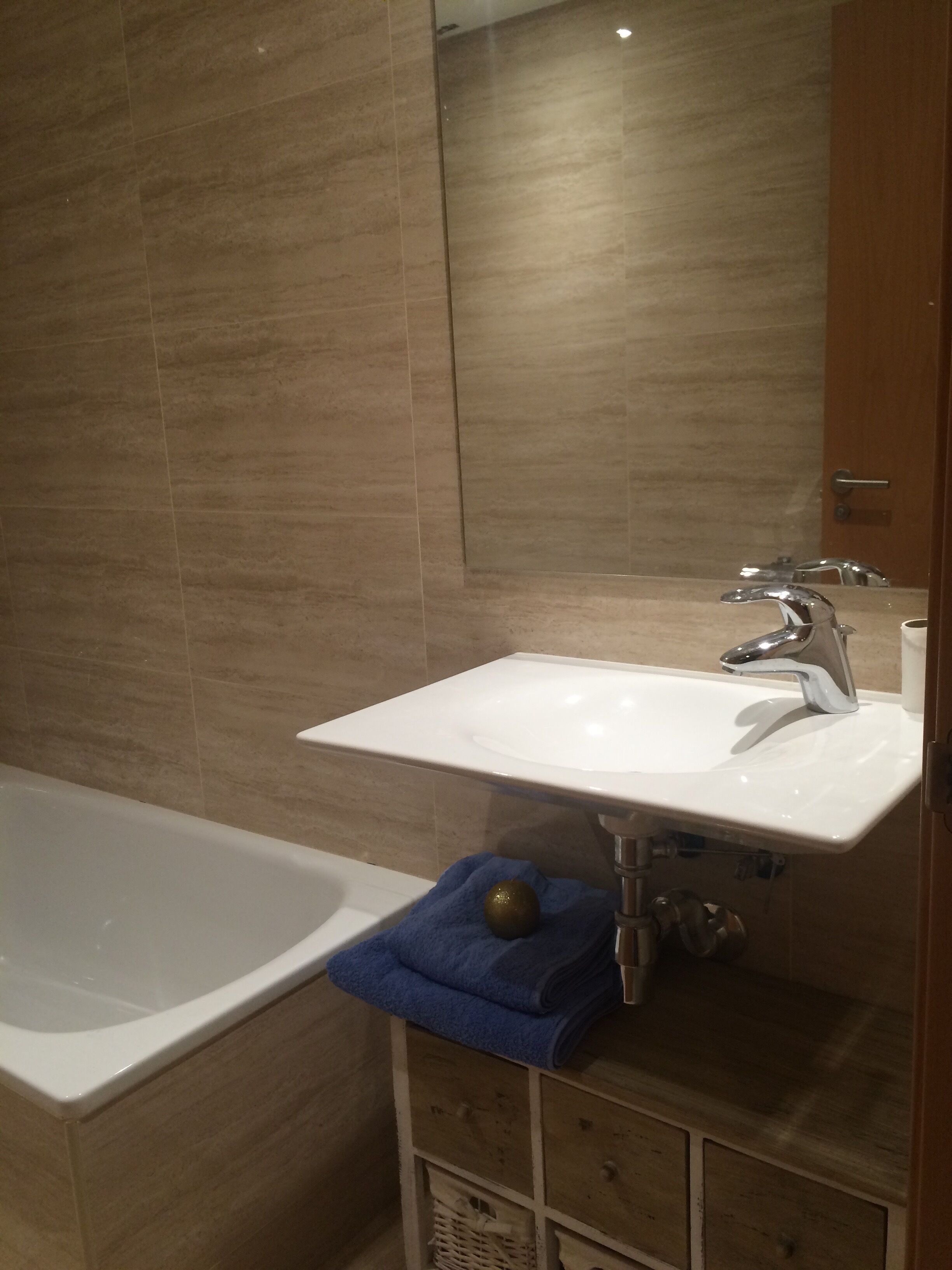 Une salle de bain avec un lavabo blanc, un miroir et une baignoire.