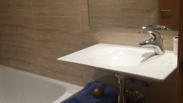 Une salle de bain avec un lavabo blanc, un miroir et une baignoire.