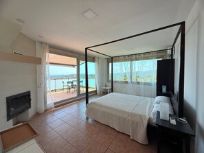 A bedroom with a four-poster bed, a television, and a view of a lake. - Club Villamar - Very spacious  villa with a large swimming pool and breath-taking view over the a... (Lloret de Mar)