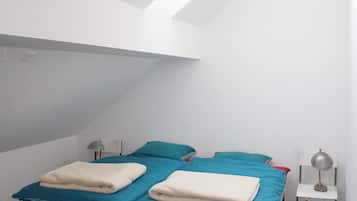 Cozy retreat with a bed under a sloped ceiling, featuring a bedside table and lamp.