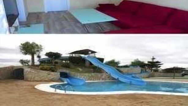 Een kamer met een bed, een rode bank en een raam met uitzicht op een zwembad en een glijbaan.