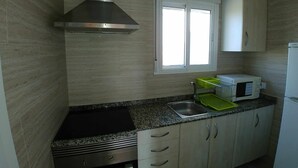 Een keuken met granieten aanrechtbladen, roestvrijstalen apparatuur en kastjes van licht hout.