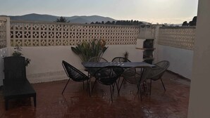 Een terras met een tafel, stoelen, een bank en een sierhekwerk.