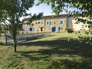 A stone building with multiple windows and shutters, surrounded by a wooden fence and a grassy lawn. - Period Farmhouse, sleeps 12, large 12m x 6m pool, barn, big garden, courtyard (Verfeil)
