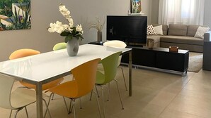 A modern living room with a dining area, featuring a flat-screen TV, a sofa, and a coffee table. - Holiday home with garden near Balestrate Beach (balestrate)