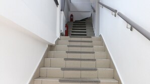 A staircase with beige steps and grey risers, leading to a landing with a fire extinguisher. - Apartment Ria, Apartments Pejton Ilidža Sarajevo (Sarajevo)