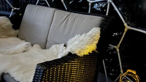 A wicker sofa with cushions, a glass table with two wine glasses and a candle, and a decorative lantern. - Lovely Waterfront Suite near Portsmouth (Dover)