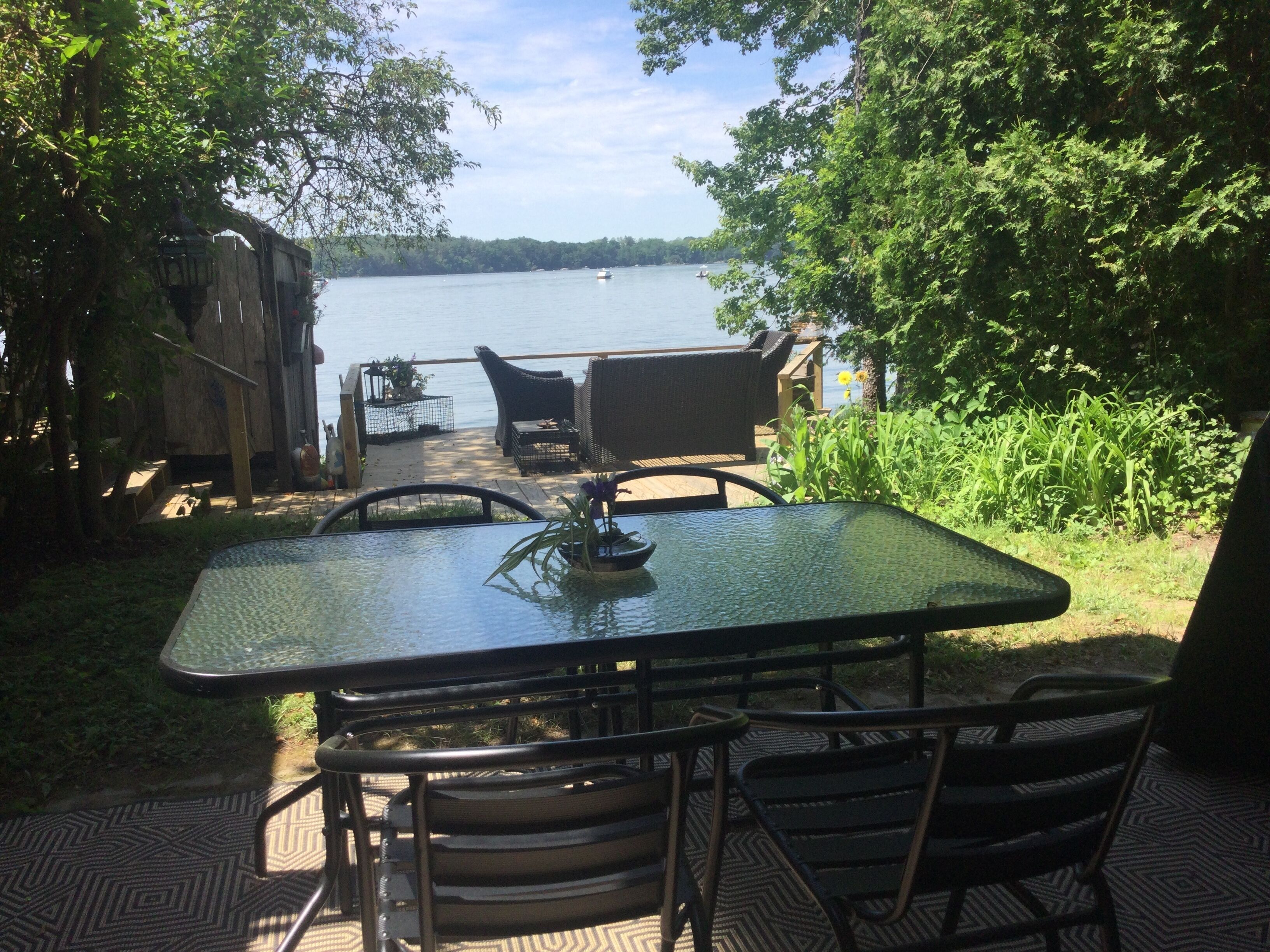 An outdoor dining area with a table and chairs, overlooking a lake.
