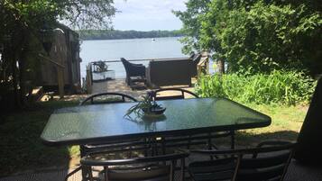 An outdoor dining area with a table and chairs, overlooking a lake.