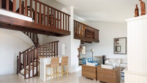 A spacious living area with a wooden staircase, wicker furniture, and a white sofa. - Provençal 10 people villa with heated pool and panoramic sea view (Mandelieu-la-Napoule)