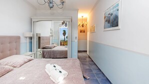 A bedroom with a large bed, a nightstand, a mirror, and a view of the outside. - Provençal 10 people villa with heated pool and panoramic sea view (Mandelieu-la-Napoule)