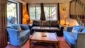 Ein gemütliches Wohnzimmer mit einer Ledersofa, zwei Sesseln, einem Couchtisch und einem Kamin.