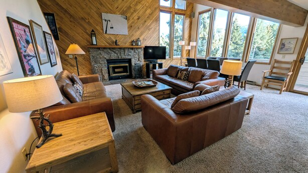 A cozy living room with a stone fireplace, leather sofas, and a television.