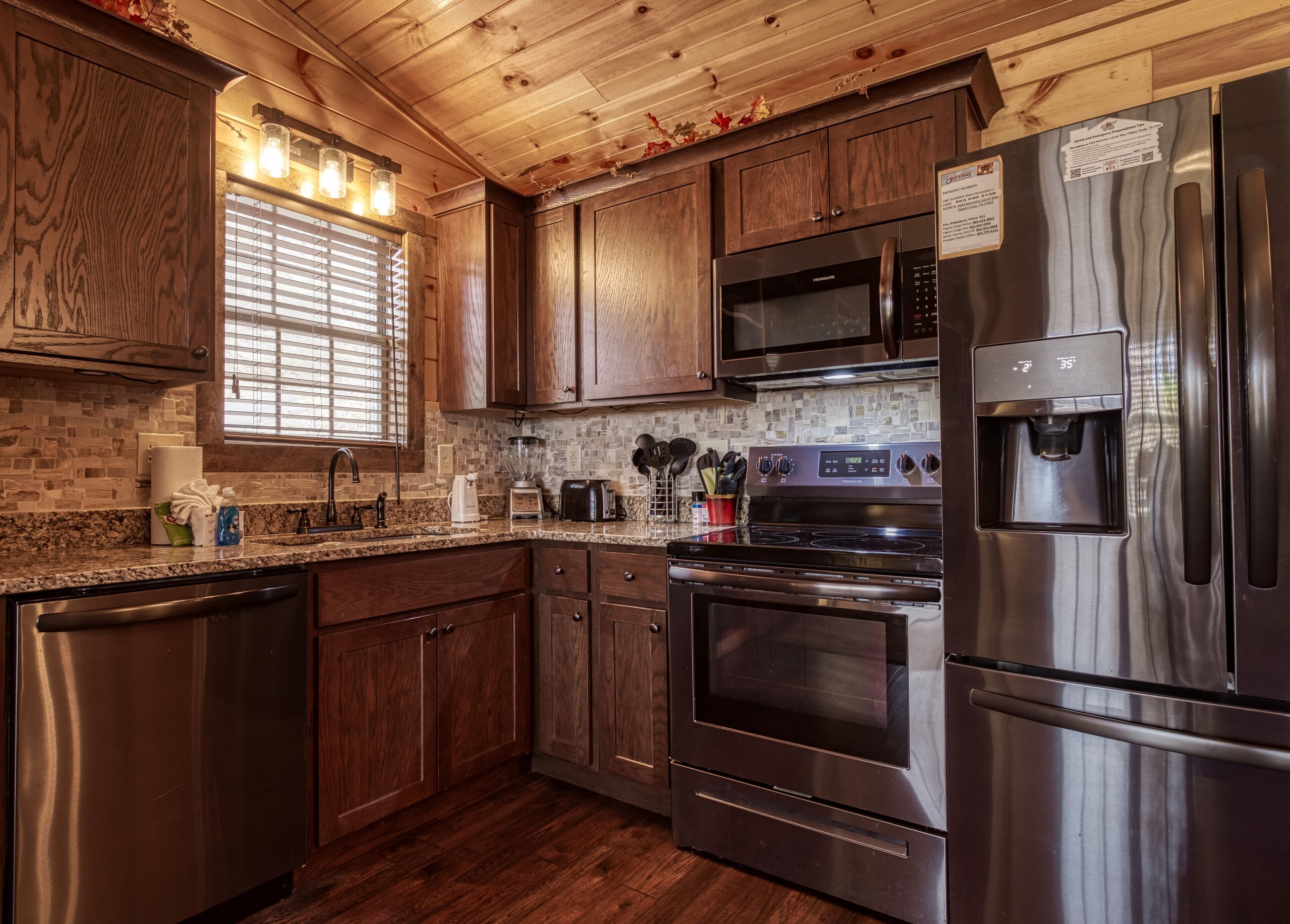 A modern kitchen with stainless steel appliances, wooden cabinets, and a granite countertop.