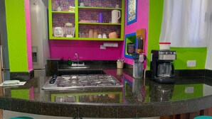 A kitchen with a central island, green and pink walls, a coffee maker, and a sink. - Akumal Paradise Private Studio - WiFi, Air Conditioning (Akumal, Riviera Maya)