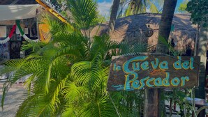 A wooden sign with the text "La Cueva del Lector" in a stylized font, surrounded by lush green foliage. - Akumal Paradise Private Studio - WiFi, Air Conditioning (Akumal, Riviera Maya)